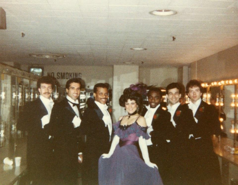Bruce Heath in a tux along with other performers pose backstage of the Academy Awards